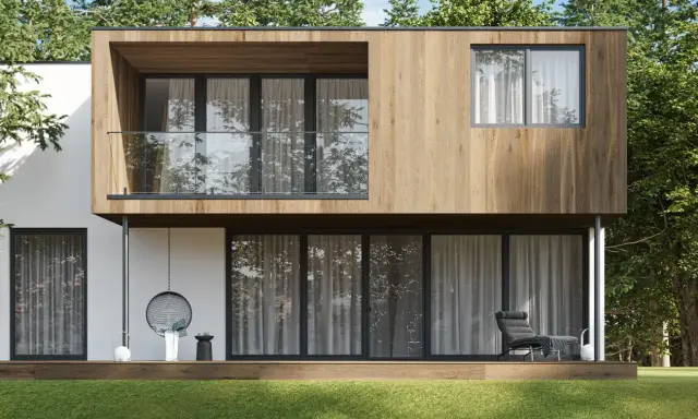 Maison modulaire moderne avec bardage bois, balcon vitré et grande baie vitrée donnant sur un jardin verdoyant.