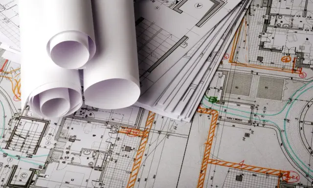 Planos arquitectónicos enrollados y apilados, listos para la construcción.
