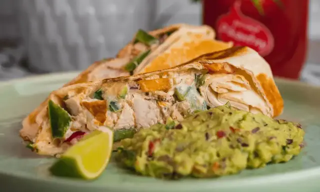 Roladka z tortilli z kurczakiem i warzywami, podana z guacamole i ćwiartką limonki. Idealny sos do tortilli!