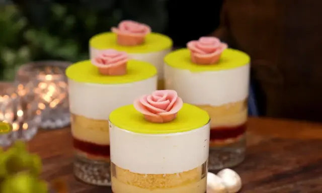 Fyra små prinsesstårta i glas, dekorerade med rosa marsipanrosor och gul marsipanlock. En festlig dessert.