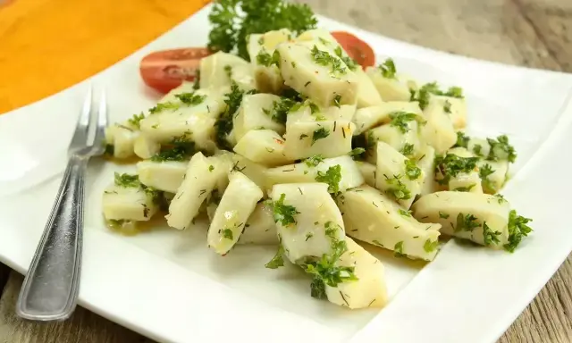 Délicieuse seiche en persillade, servie sur une assiette blanche avec une touche de tomate et de persil frais. Un plat savoureux et léger.