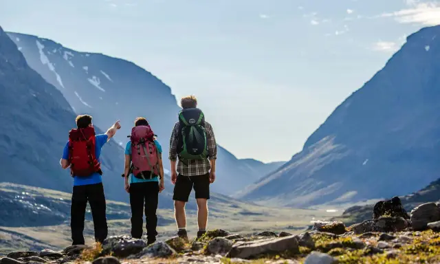 Vandrare med ryggsäckar njuter av den storslagna utsikten över fjällen under en abisko sommar.