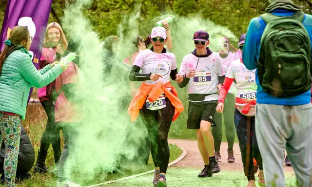 Uczestnicy biegu w kolorowym proszku, w tym 3 forma run, biegną wśród zielonej chmury.
