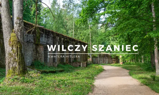 Wilczy Szaniec, dawna kwatera Hitlera, otoczona bujną zielenią. Kamienne mury i leśna ścieżka tworzą atmosferę minionych czasów.
