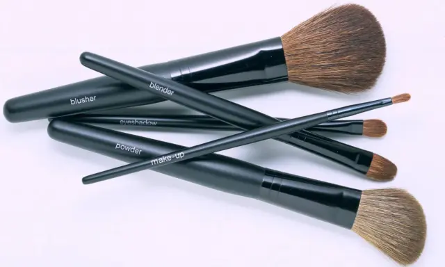 Un conjunto de brochas de maquillaje negras etiquetadas como "blusher", "blender", "eyeshadow", "powder" y "make-up". Aprende como limpiar brochas de maquillaje para mantenerlas en perfecto estado.