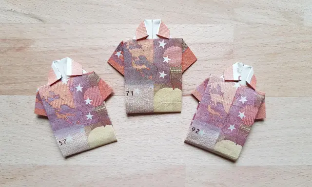 Drei Hemden aus gefalteten Euro-Scheinen. Kreative Geld Formen auf Holzhintergrund.