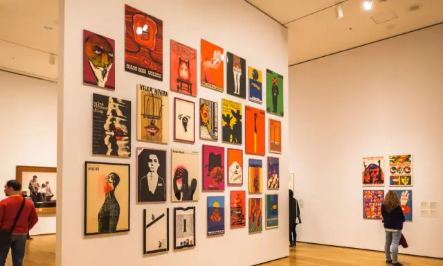 Vibrant posters adorn a gallery wall, showcasing diverse graphic design. This exhibition highlights some of the best art cities in the US.