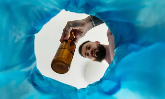 Mężczyzna wyrzuca butelkę, symbolizując wolność i nowe życie bez alkoholu.