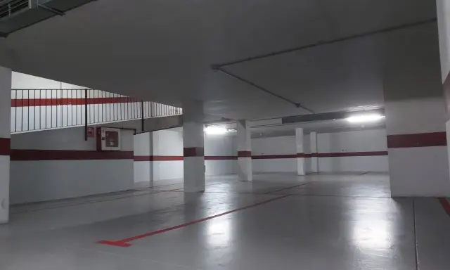 Un garaje particular recién pintado, con líneas rojas en el suelo y paredes blancas con franjas rojas.
