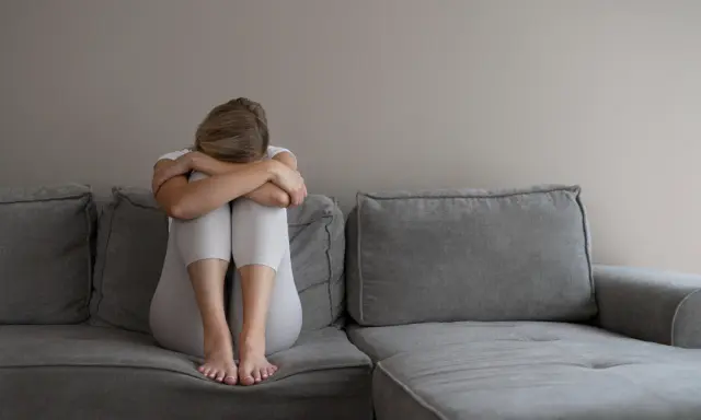 Kobieta z depresją siedzi skulona na kanapie, przygotowując się do komisji lekarskiej ZUS. Co mówić, by uzyskać pomoc?