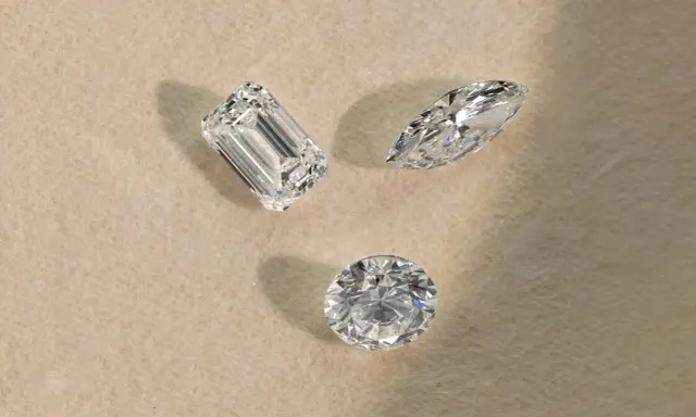 Tre diamanti di taglio diverso (smeraldo, marquise, rotondo) su sfondo chiaro, pronti per la classificazione diamanti.