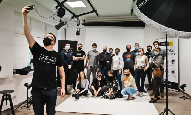 Grupa entuzjastów fotografii na zajęciach w szkole fotografii. Uczestnicy pozują do wspólnego zdjęcia w studiu.