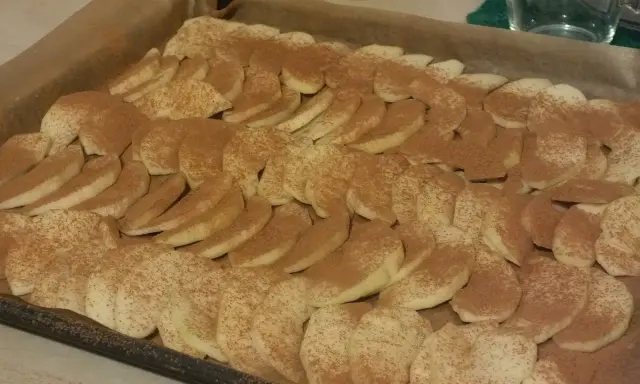 Odwrócona rolada z jabłkami, posypana cynamonem, czeka na upieczenie.