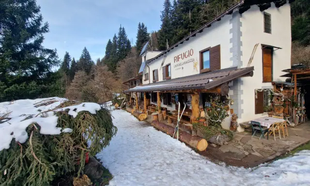 Rifugio Cimon della Bagazza, un luogo accogliente con rifugi aperti in inverno in Lombardia, circondato da neve e alberi.