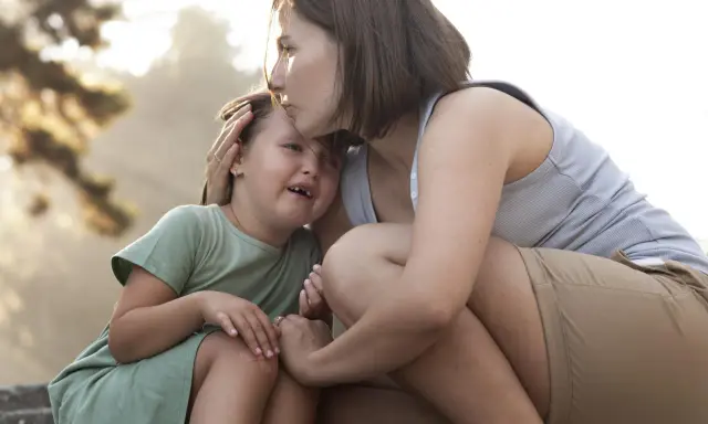 Madre consola la figlia che piange, un abbraccio che mostra le diverse tipologie di attaccamento sicuro e amorevole.
