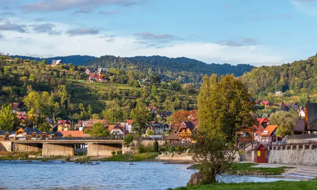 Widok na malownicze ulice w Szczawnicy, z domami na zboczach gór i rzeką w tle.
