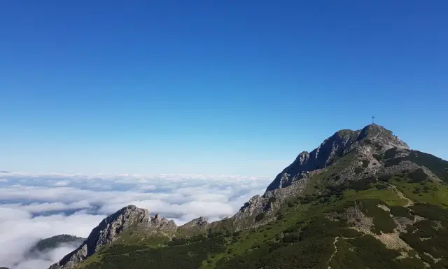 Giewont wysokość 1894 m n.p.m. widoczna z grani, morze chmur poniżej, błękitne niebo.