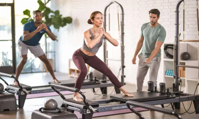 Persone che praticano pilates su reformer, un allenamento che migliora forza e flessibilità.