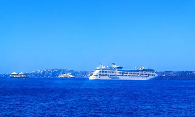 Grandi navi da crociera Royal Caribbean navigano in acque blu, con isole sullo sfondo.