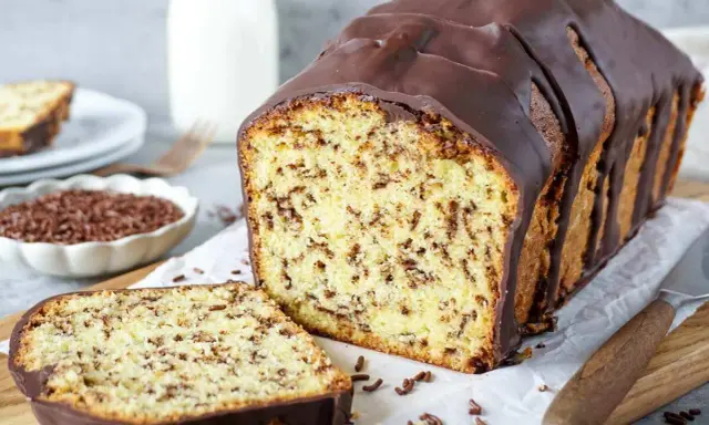 Ein saftiger, gesunder Kuchen mit Schokoladenstückchen und dunkler Glasur, daneben eine Scheibe und eine Schale Streusel.