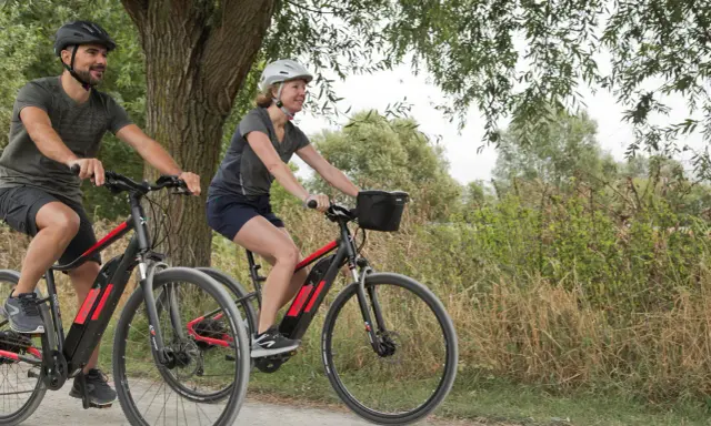 Para pozdrawia, jadąc na rowerach hybrydowych. Silnik wspomaga jazdę, ułatwiając pokonywanie wzniesień i dłuższych tras.