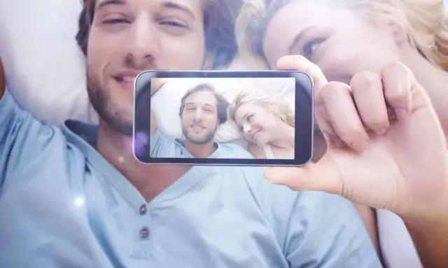 Para widzi na ekranie telefonu siebie, uśmiechnięci i blisko. To piękne objawy zauroczenia.