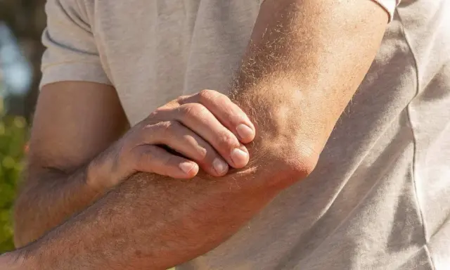 Mann hält seinen Arm, da er Ellenbogen Schmerzen beim Strecken hat.