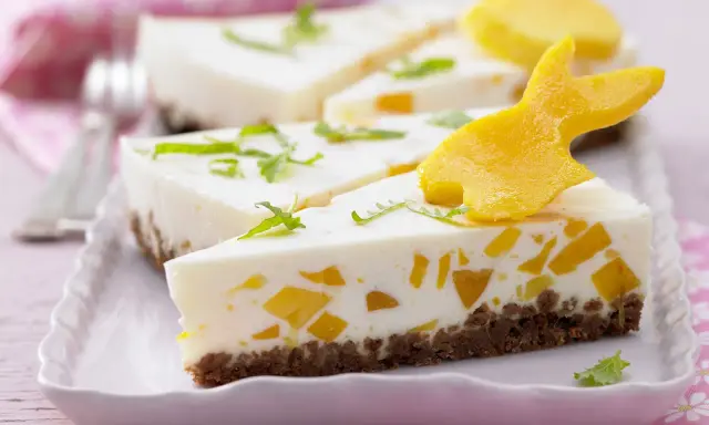 Süße Ostertorten Rezepte: Cremiger Kuchen mit Mango-Stückchen und Osterhasen-Deko aus Mango.