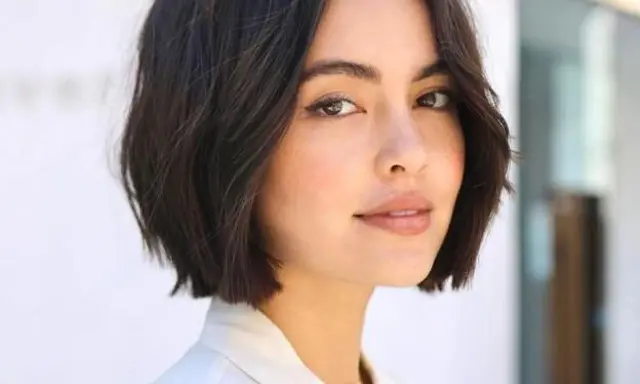 Mujer con un moderno corte de pelo bob oscuro y ondulado, luciendo un estilo chic y juvenil.
