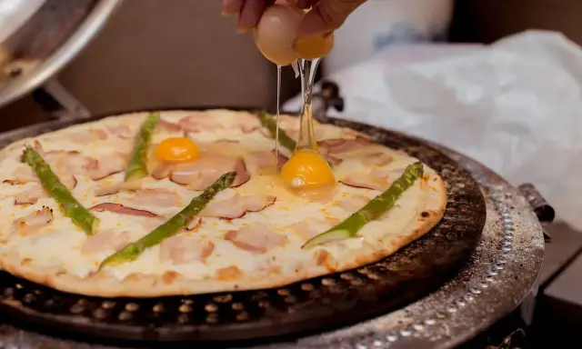 Na pizzę z boczkiem i szparagami dodawane jest jajko.