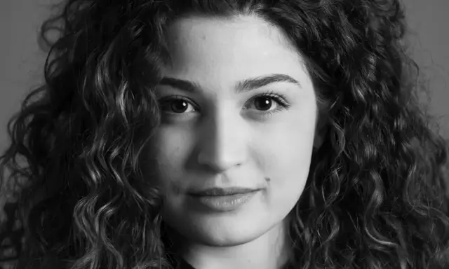 Primo piano di una giovane donna con capelli ricci, un esempio di diversi tipi di ritratto che catturano espressioni uniche.