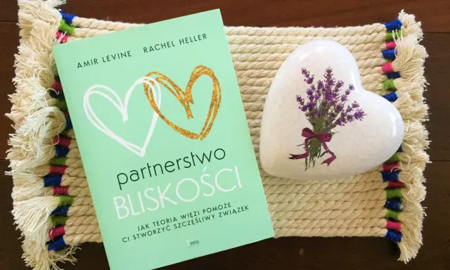 Książka "Partnerstwo bliskości. Jak teoria więzi pomoże Ci stworzyć szczęśliwy związek" obok serca z lawendą.