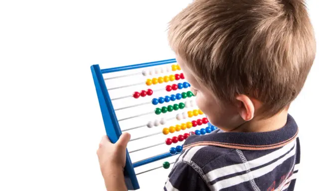 Jongen met telraam, leert getallen en patronen. Dit is een vorm van assimilatie en accommodatie in de ontwikkeling.