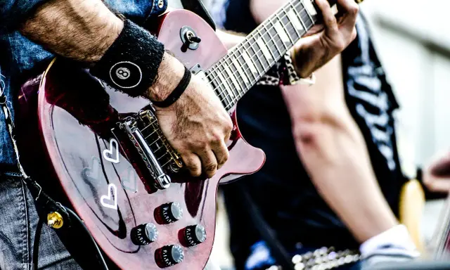 Muzyk gra na gitarze, przygotowując się do wykonania coverów piosenek.