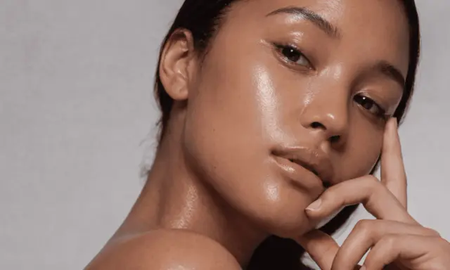 Rostro de mujer con piel glowy, hidratada y radiante. Su mano acaricia suavemente su barbilla.