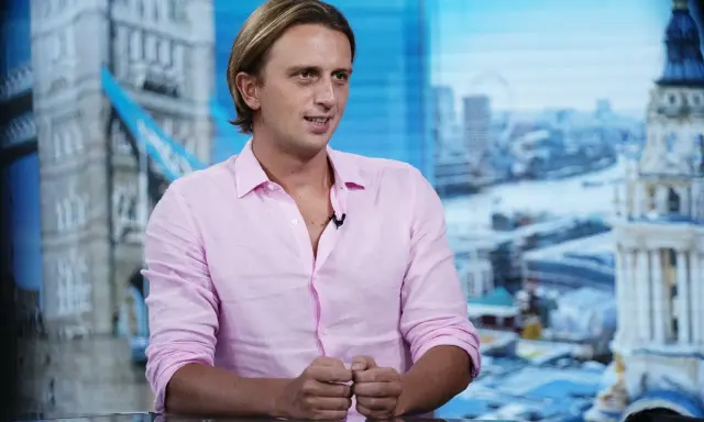 Nikołaj Storonski w różowej koszuli, na tle panoramy Londynu z Tower Bridge.
