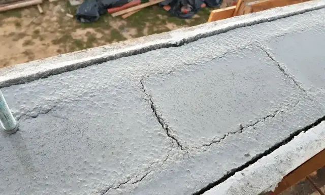 Pęknięty wieniec budowlany, widoczny na tle placu budowy.