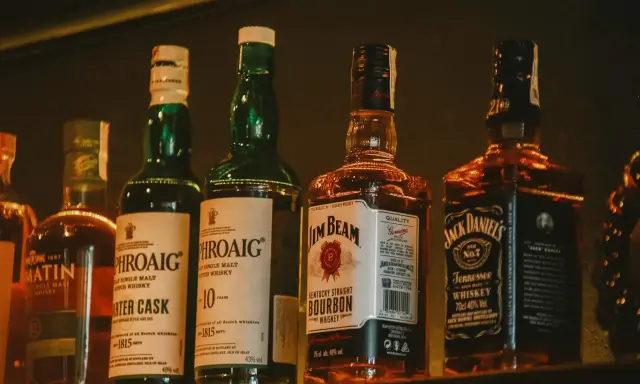 Rząd butelek whisky: Laphroaig, Jim Beam i Jack Daniel's.