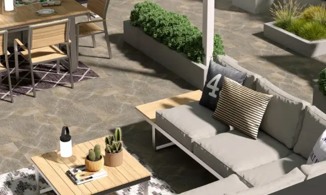 Un elegante giardino pavimentato moderno con divano, tavolo da pranzo e piante.