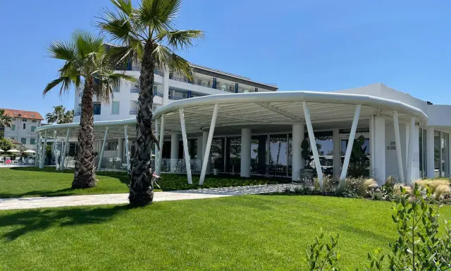 Palme e prato verde davanti a un moderno ristorante a Bellaria Igea, con un edificio bianco sullo sfondo.