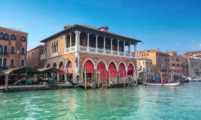 Le marché du Rialto à Venise, avec ses étals colorés et ses gondoles sur le Grand Canal.