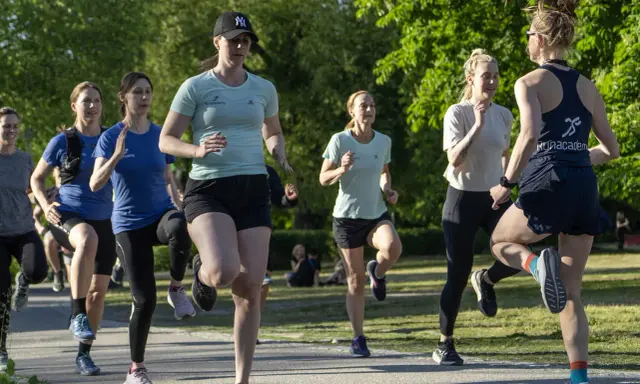 Grupp kvinnor tränar löpning i parken, ett intensivt backintervaller pass.