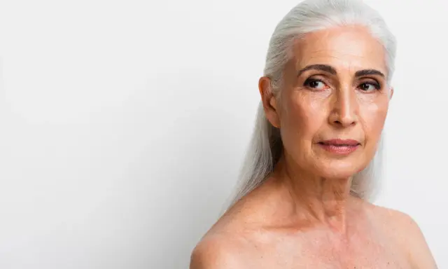 Visage femme 70 ans, cheveux argentés, regard pensif tourné vers la droite.