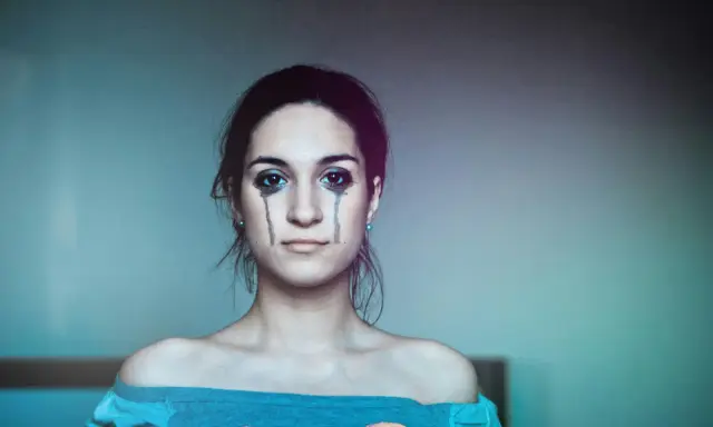 Ragazza con trucco che simula lacrime, espressione di labilità emotiva, alla ricerca di cura e comprensione.