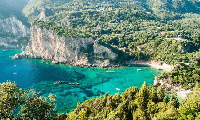 Baia verde smeraldo a Corfu, perfetta per una vacanza con bambini. Scogliere imponenti e acque cristalline invitano al gioco e all'esplorazione.