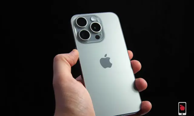 Dłoń trzyma srebrny iPhone 15 Pro z widocznym modułem aparatów i logo Apple. Dynamic Island na ekranie tego modelu to innowacja.