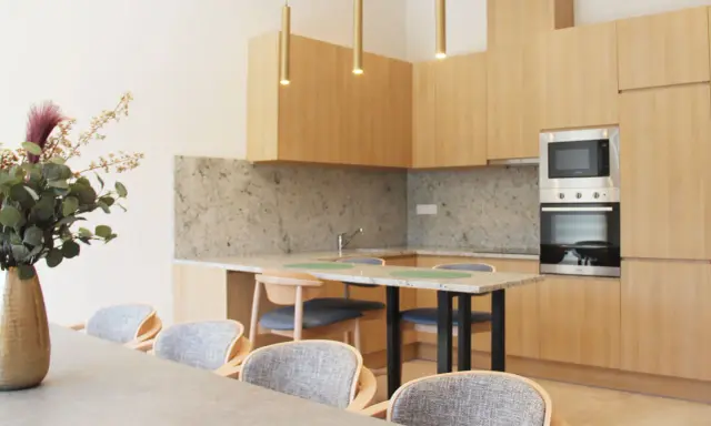 Estudio moderno en Livensa Living Studios Málaga Feria, con cocina equipada, encimera de granito y comedor con sillas cómodas.