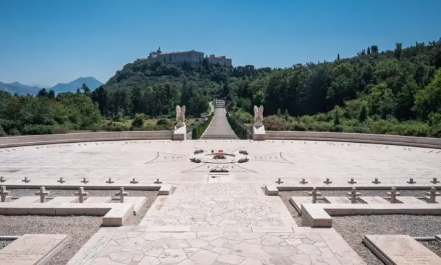 Cmentarz żołnierzy polskich, gdzie jest Monte Cassino. Monumentalny widok na wzgórze z opactwem, schody, krzyże i kamienne nagrobki.