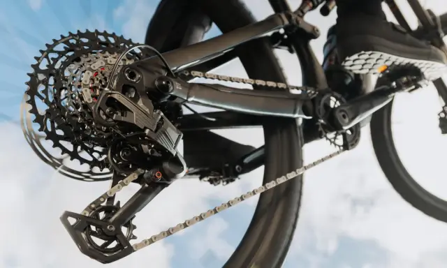 Nahaufnahme einer SRAM Schaltung am Fahrrad. Die Kette läuft über die Kassette, während ein Schuh auf dem Pedal zu sehen ist. Perfekt, um die SRAM Schaltung einzustellen.
