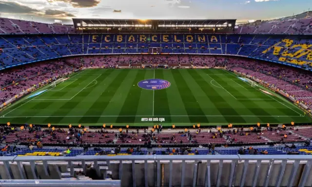 Widok na stadion Camp Nou podczas remontu, z trybunami w kolorach FC Barcelony i oświetlonym boiskiem.